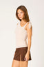 Woman wearing a beige sleeveless top and brown skirt on a white background