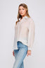 Woman wearing a light-colored shirt and blue jeans on a white background