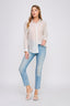 Woman wearing a light-colored shirt and blue jeans on a white background