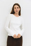 Woman wearing a white sweater against a plain background