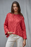 Woman wearing a red cable knit sweater against a gray background
