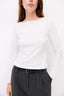 Person wearing a white long-sleeve top and gray pinstripe pants on a white background