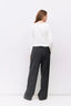 Person wearing a white top and dark gray pants against a white background