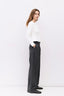 Woman wearing a white sweater and dark pants on a white background