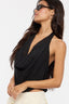 Woman wearing a black halter top with a plain background
