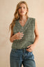 Woman wearing a green knitted sleeveless sweater and blue jeans on a beige background
