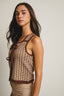Woman wearing a brown and beige sleeveless top against a plain background