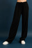 Black wide-leg pants worn by a person on a blue background