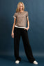 Woman wearing a patterned top and black pants against a blue background