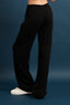 Person wearing black wide-leg pants on a dark blue background