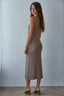 Woman wearing a brown ribbed dress against a plain background