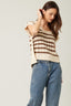 Woman wearing a striped sweater and jeans against a plain background