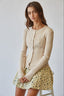 Woman wearing a beige ribbed sweater and floral skirt on a white background