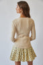 Woman wearing a beige ribbed sweater and floral skirt on a plain background