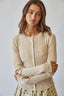 Woman wearing a beige ribbed sweater against a plain background