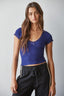 Woman wearing a blue top and black pants against a gray background