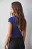Woman wearing a blue top and black pants against a plain background