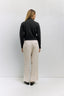 Person wearing a black sweater and beige pants against a white background