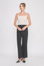 Woman wearing a white tank top and black pants on a white background