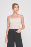 Woman wearing a white tank top and black pants on a plain background