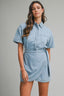 Woman wearing a denim wrap dress against a gray background