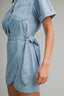 Light blue denim dress with a tie waist on a gray background