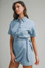 Woman wearing a light blue denim dress against a gray background