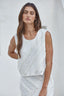 Woman wearing a white sleeveless top and skirt against a light background