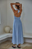 Woman in a light blue dress standing in a room with a neutral color palette.