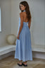 Woman wearing a light blue dress standing in a minimalistic room.