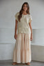 Woman wearing beige tiered wide leg flowy pants against a plain background
