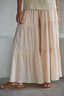 Woman wearing beige tiered wide leg flowy pants against a plain background