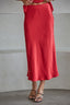 Red satin midi skirt worn by a person against a plain background