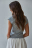 Woman wearing a gray top and white skirt against a plain background