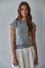 Woman wearing a gray top and white skirt against a plain background