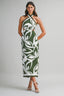 Woman wearing a green and white halter neck dress with leaf pattern on a gray background