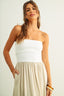 Woman wearing a white strapless beige maxi dress on a plain background