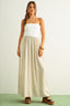 Woman wearing a white strapless beige maxi dress on a plain background