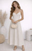 Woman in a white dress holding a small handbag in a minimalistic setting