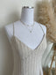 White jewelry display mannequin with a necklace on a neutral background