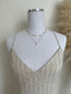 Mannequin wearing a light-colored dress with a necklace on a neutral background