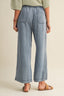 Person wearing light blue denim pants on a beige background