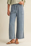 Person wearing light blue denim wide-leg pants on a beige background