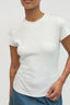 Person wearing a plain white t-shirt against a light gray background