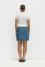 Person wearing a white t-shirt and blue denim skirt on a white background