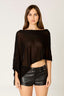 Woman wearing a black top and leather shorts on a plain background