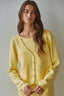 Woman wearing a yellow cardigan against a plain background