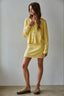Woman wearing a yellow outfit against a plain background