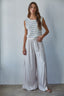 Woman wearing a striped sleeveless top and wide-leg pants against a plain background