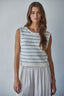 Woman wearing a sleeveless striped top and light-colored pants against a plain background